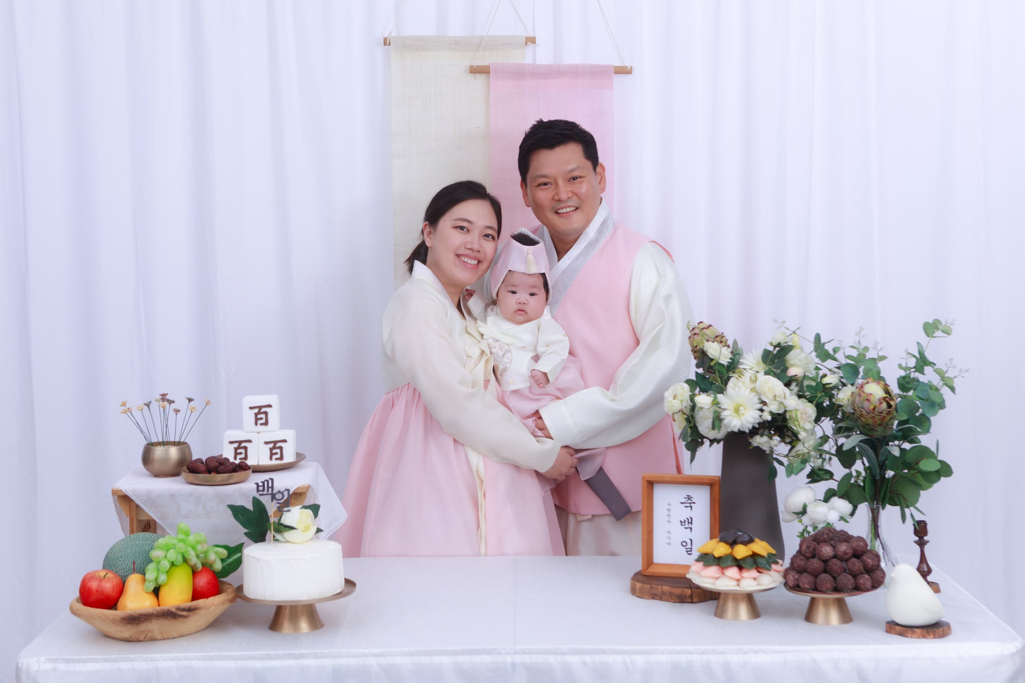 분홍 한복을 맞춰 입은 부모와 아기의 백일 촬영